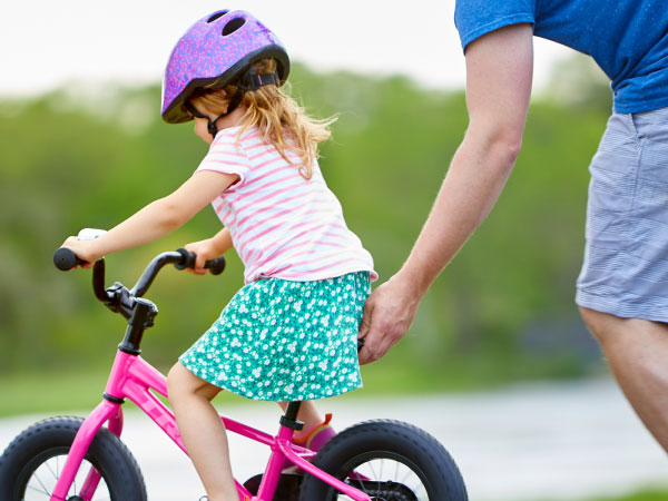 Child riding kids bike rental on Nantucket with parent